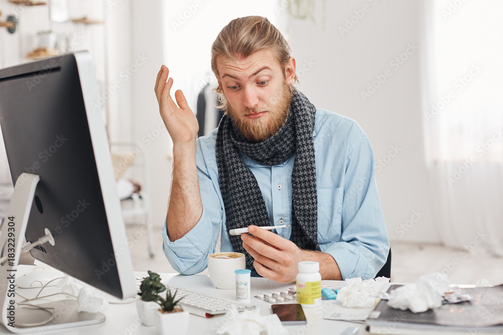 Health problems concept. Astonished young bearded office worker has a