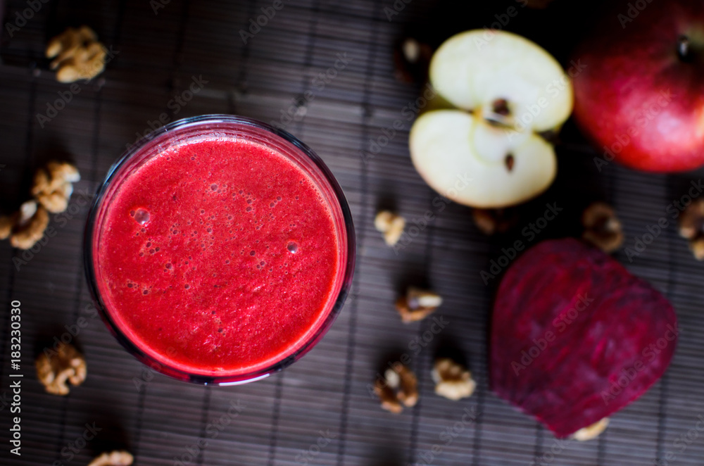 Fresh raw vegetarian red smoothie made from beetroot, carrot, apple and walnuts on the dark, wooden background, overhead view