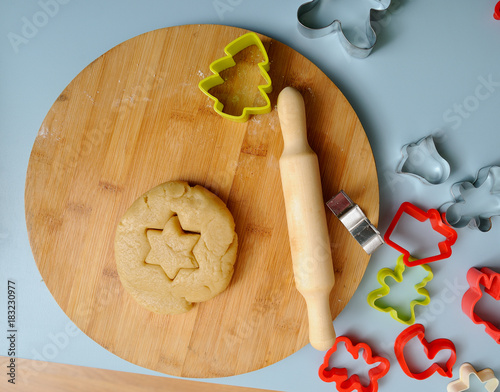 Making homemade Christmas cookies. Rolling pin, cookie cutters and cookie dough on wooden board