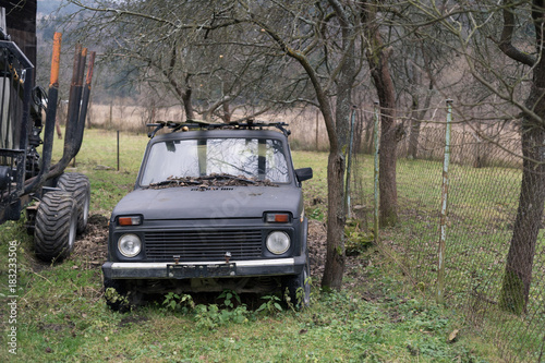 Retro and vintage russian and soviet vehicle in the garden and countryside. Bare trees are behind off-road car. Dull and muted colors during autumn and fall.