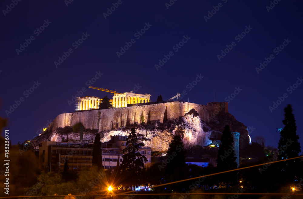 Illuminated Acropolis with Parthenon at night with the hill of Lycabetus and nice clouds, Greece.