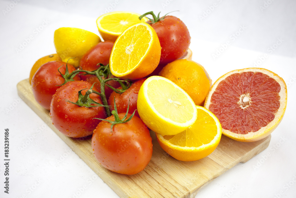 Tomato and orange on the white background with green leafs on th Tomato and orange on the white background with green leafs on th