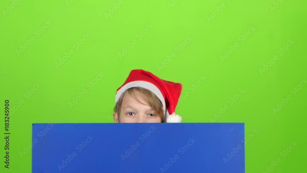 Teenager in a red hat appears from a board on a green screen. Slow motion Teenager in a red hat appears from a board on a green screen. Slow motion