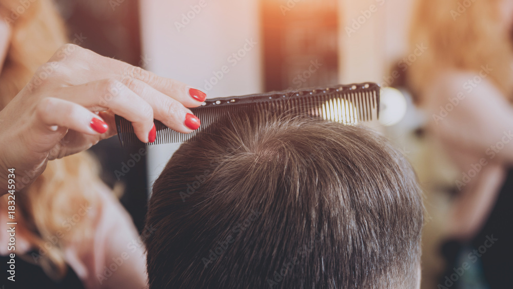 Naklejka premium Master cuts hair and beard of men, hairdresser makes hairstyle for a young man. Hipsters