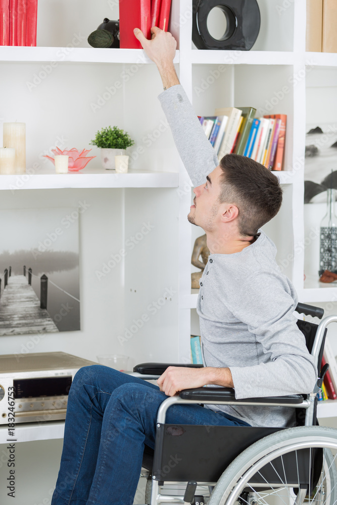 man on the wheelchair reaching for a book man on the wheelchair reaching for a book
