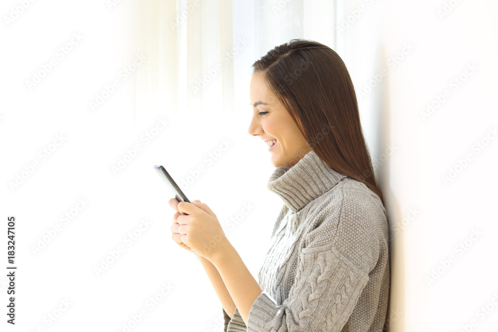 Woman using a smart phone indoors in winter Woman using a smart phone indoors in winter