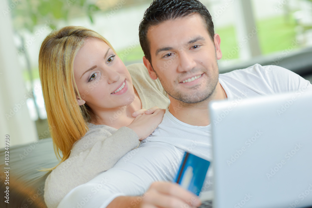 Couple looking at laptop, holding credit card Couple looking at laptop, holding credit card