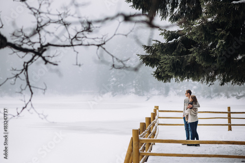 Young beautiful couple staying near the winter mountain lake photo