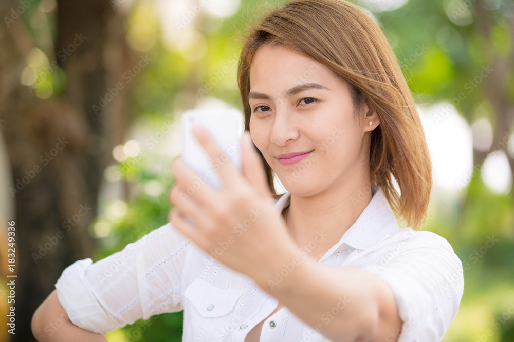 Asian woman holding smartphone digital camera with her hands and taking a selfie Asian woman holding smartphone digital camera with her hands and taking a selfie