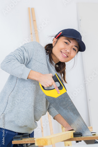 girl is sawing a wooden beam the hand saw