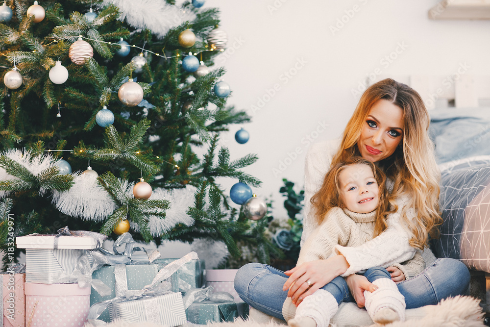 mother and daughter sitting by the christmas tree mother and daughter sitting by the christmas tree