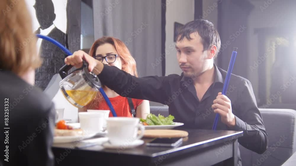 Happy group of friends chatting having drinks in coffee shop - smoking hookah Happy group of friends chatting having drinks in coffee shop - smoking hookah