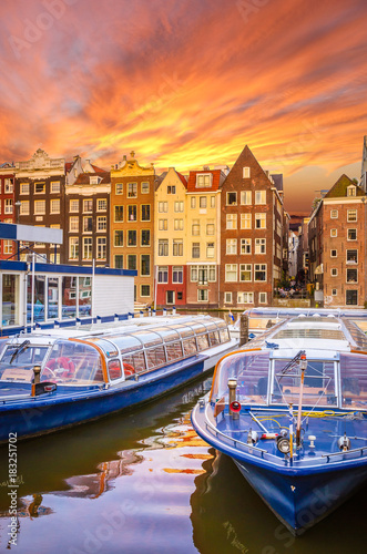 Traditional old buildings and boats at sunset in Amsterdam  Netherlands.