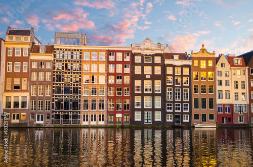 Traditional old buildings and boats at sunset in Amsterdam, Netherlands.