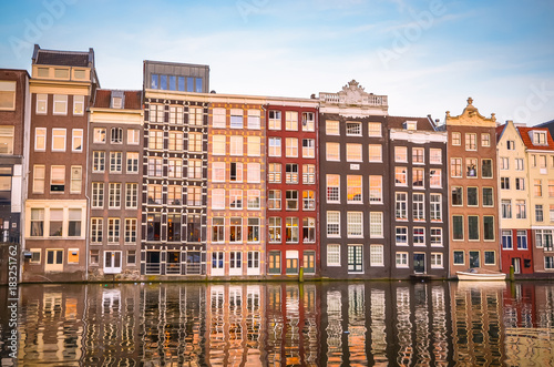 Traditional old buildings and boats at sunset in Amsterdam, Netherlands.