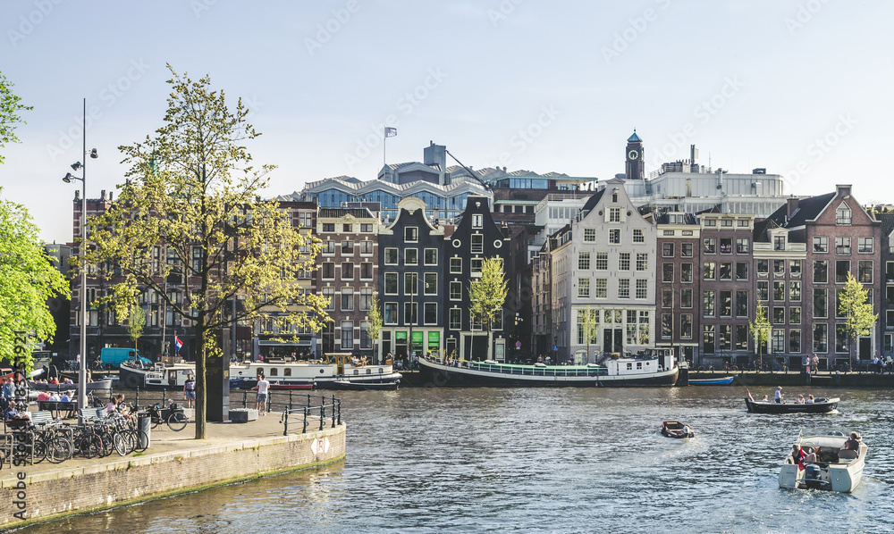 Naklejka premium Traditional old buildings and and boats in Amsterdam, Netherlands. Canals of Amsterdam.