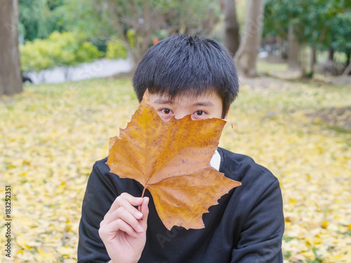 Portrait of handsome Autumn Chinese man with Autumn Leaves on Fall Nature Background.