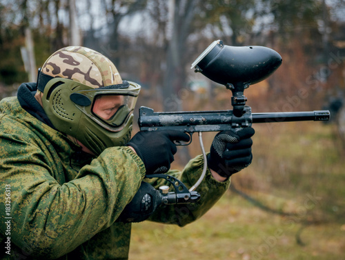 Man with gun playing at paintball. Outdoors