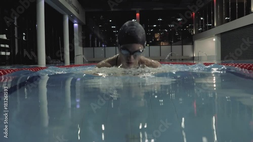 Sports woman floating breaststroke style in blue water swimming pool