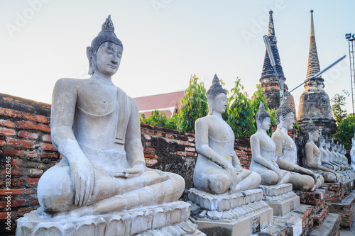 Aligned Sitting Buddha Statues with ancient ruin of temple at wat yai chaimongkol