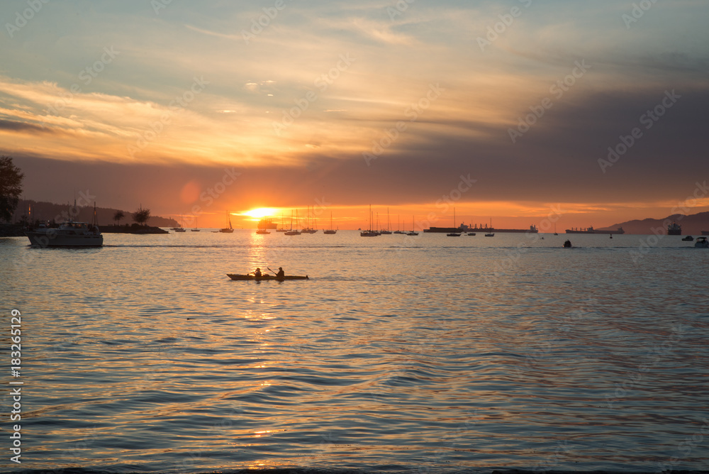 Two people kayaking during the sunset on English bay Vancouver