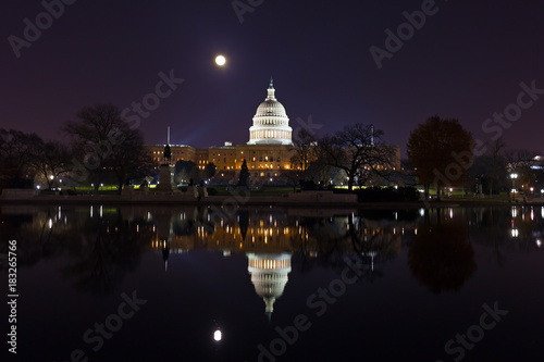 Capitol Hill panorama at night during super moon. Calm water of the pool with reflection of the dome.