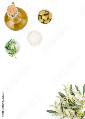 Glass bottle of premium virgin olive oil, sea salt, rosemary and some olives with olive branch isolated on a white background. Top view