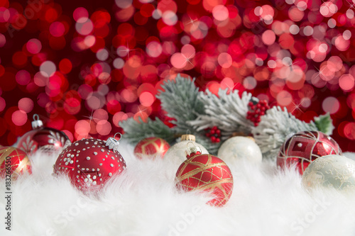 Arrangement of red and white ornaments with pine on red background
