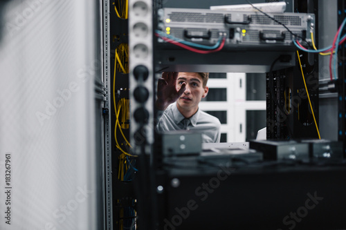 Young business man with laptop working in data center