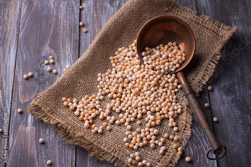 Whole yellow dried peas on sackcloth with a copper spoon, rustic style, selective focus, free space