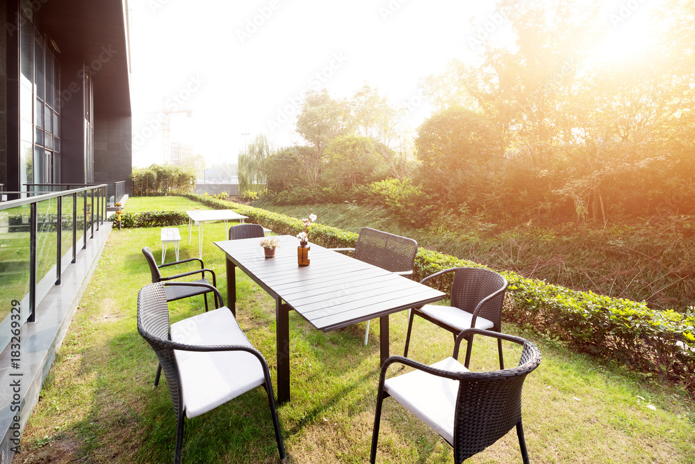 Fototapeta premium table and chairs near modern building with sunbeam