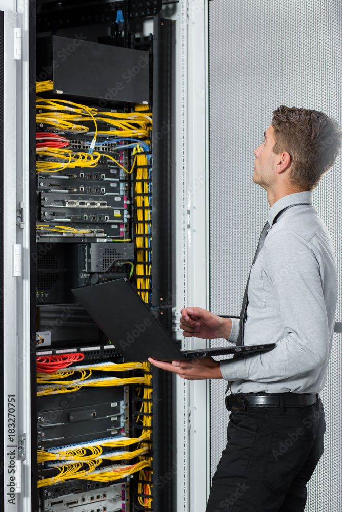 Young business man with laptop working in data center