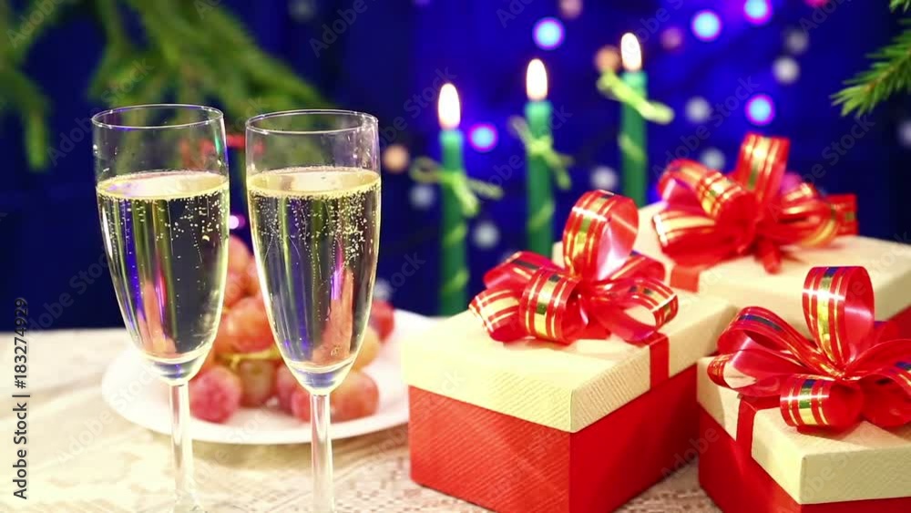 Two glasses of champagne with bubbles close-up against the background of a table with fruit and burning candles and herders blurry bokeh Two glasses of champagne with bubbles close-up against the background of a table with fruit and burning candles and herders blurry bokeh