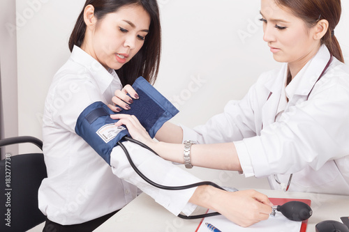 Doctor using sphygmomanometer with stethoscope checking blood pressure  to a patient in the hospital.