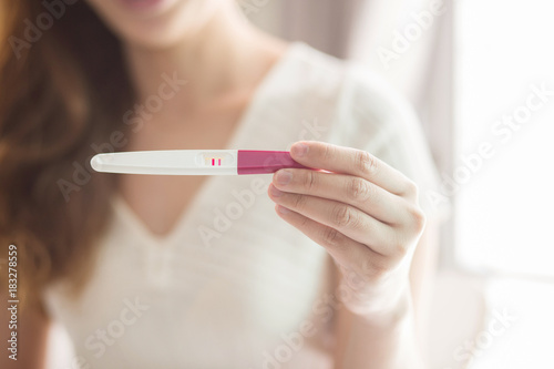 Selective focus Pregnancy test positive result on hand of woman in her bedroom,Blurred background.