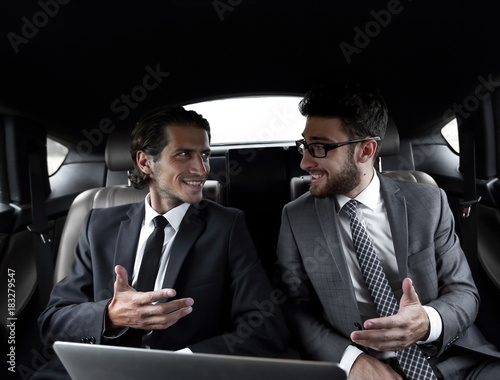 two businessman talking while sitting in the car