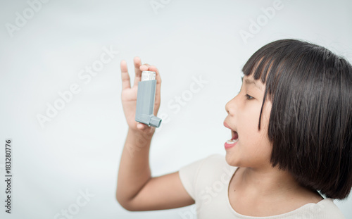 Little girl using Asthma inhaler for breathing. photo