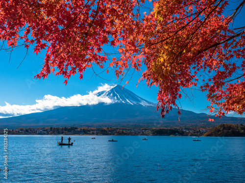 Fuji mountain with red maple and the fishermen are fishing on boat in the lake. © sakda