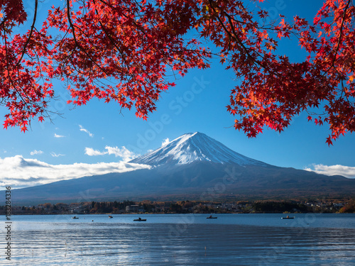 Fuji mountain with red maple and the fishermen are fishing on boat in the lake. © sakda