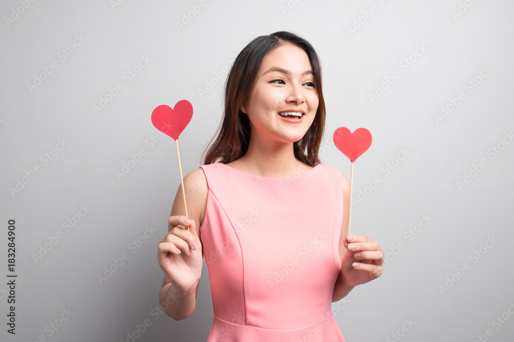 Charming asian woman holding red heart shape.