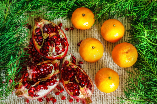 Pomegranate, grains of pomegranate, mandarins near the branches of the Christmas tree.New year concept. Flat lay. Top view