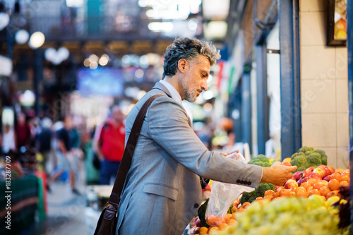 Canvas Print Mature businessman buying fruit in a city.