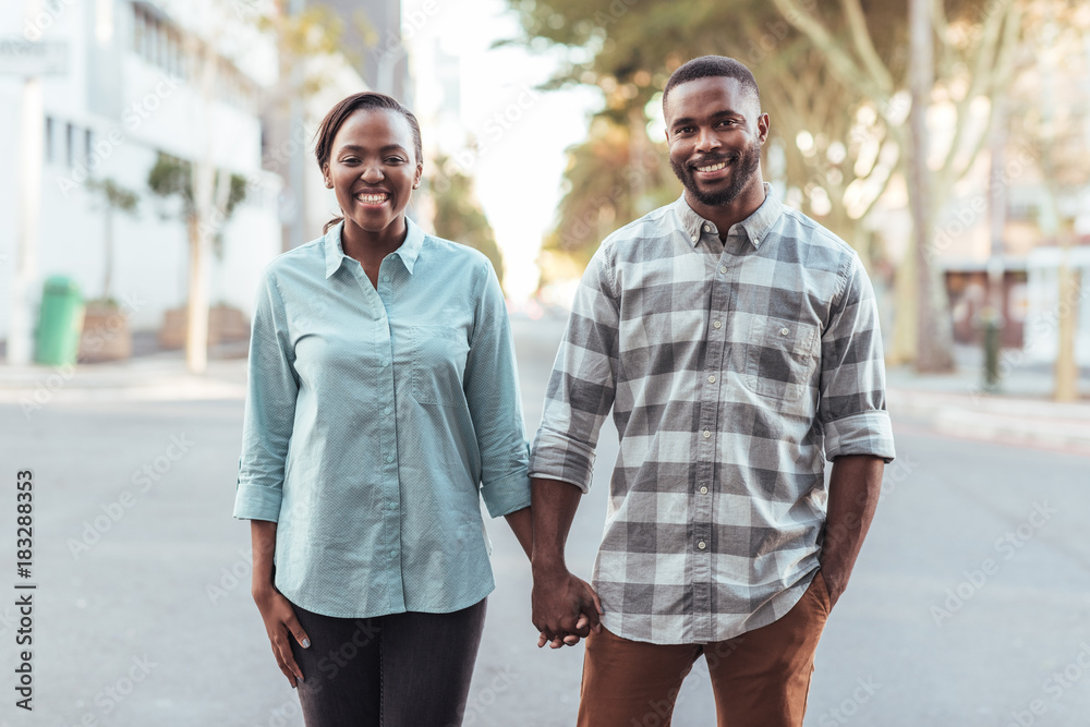 Young African couple smiling while holding hands in the city