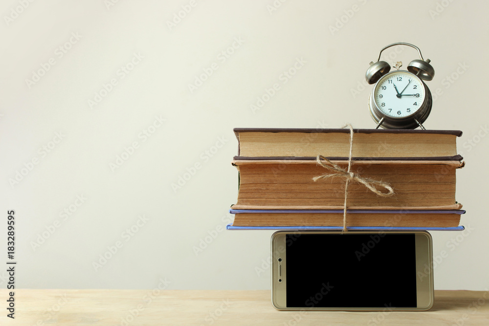 stack of books between the phone and the alarm clock
