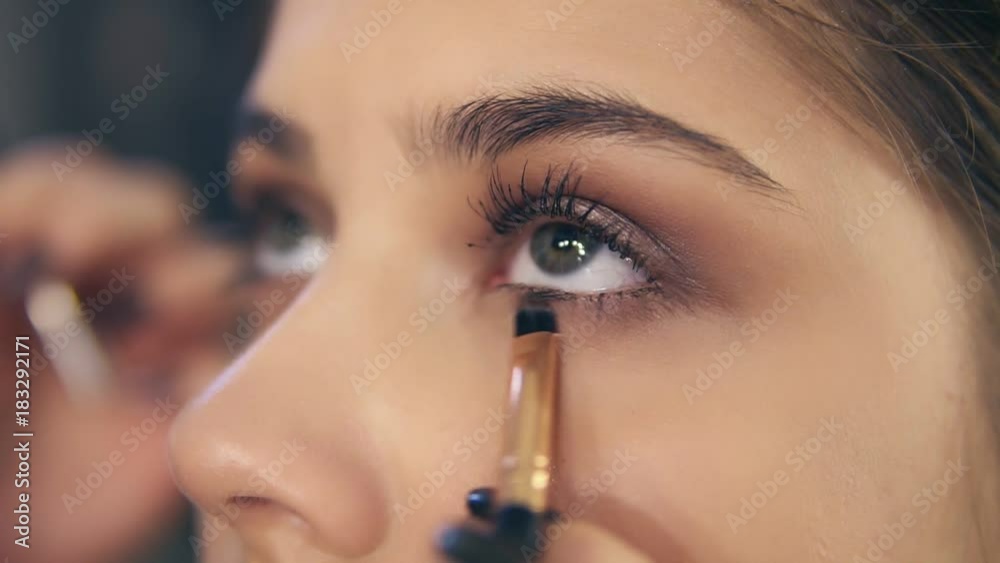Closeup view of professional makeup artist's hands using makeup brush to apply eye shadows. Slowmotion shot