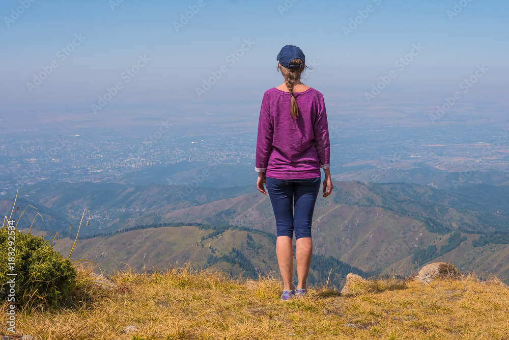 Woman looks afar in the mountains near Almaty, Kazakhstan