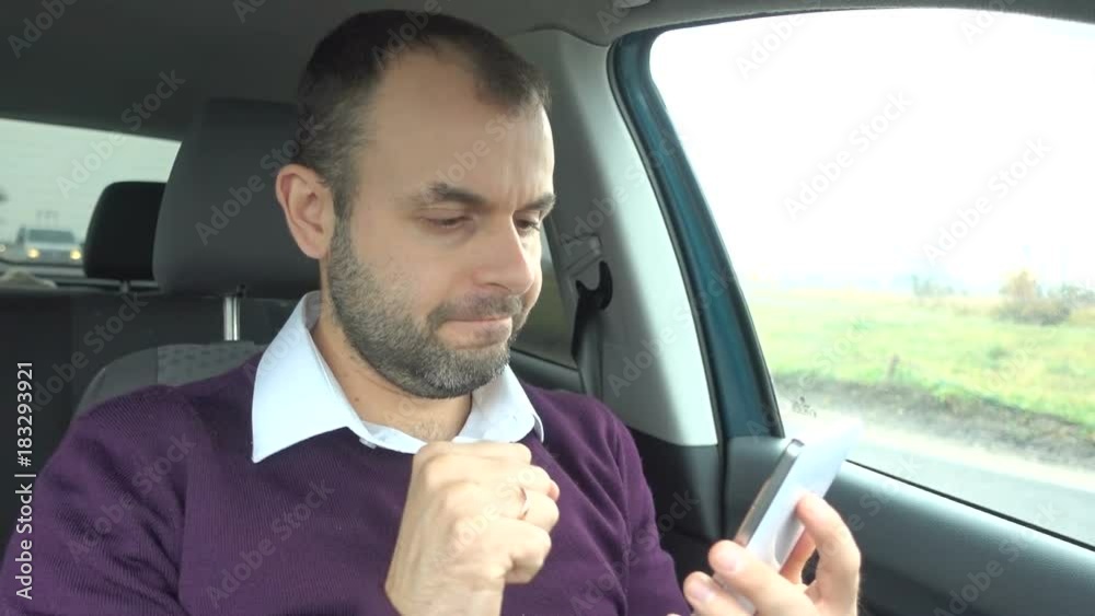 Businessman using a smartphone while sitting inside car. Man with a smart-phone in the vehicle. Businessman using a smartphone while sitting inside car. Man with a smart-phone in the vehicle.