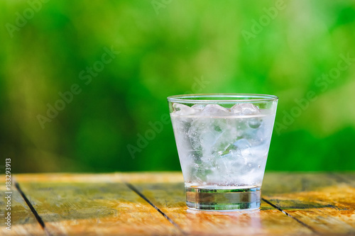 A glass of water with ice on green background