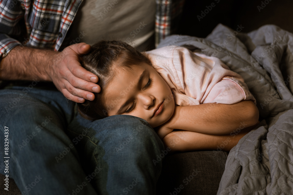 cropped image of little daughter fall asleep on fathers knees at home cropped image of little daughter fall asleep on fathers knees at home