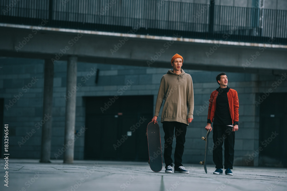 young men in streetwear outfit standing with skateboards